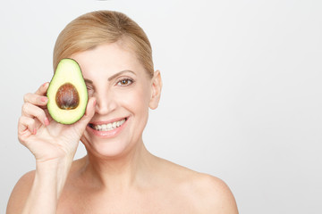 Eat healthy. Studio portrait of a gorgeous mid adult woman laughing posing with an avocado copyspace on the side