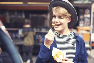Portrait of young woman with fries winking .
