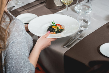 woman eating delicious salmon pasta in a restaurant. small portion