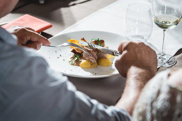 man eating delicious roulade of rabbit meat in a restaurant. small portion