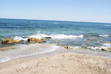 Stones on the beach, waves, beach, blue water. Summer.