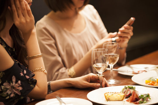 Women are watching smartphones while eating at the bar