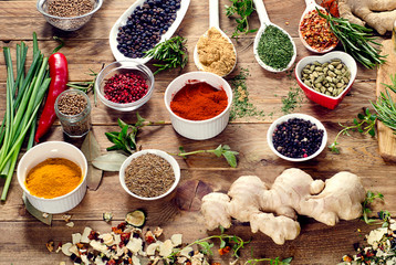 Colorful spices and fresh herbs on a wooden background.