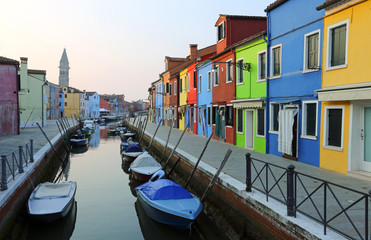 Fototapeta na wymiar Boats moored in the waterway near the colorful houses of the island of Burano in Italy