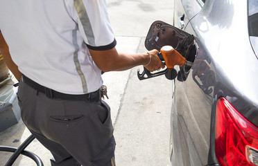 man pumping gasoline fuel in car at gas station