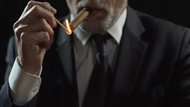 Millionaire lighting expensive Havana cigar with a match, power and authority