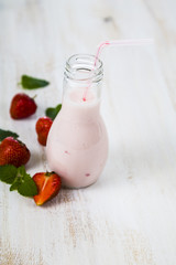 Smoothies and ripe strawberry on a wooden table.