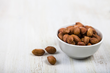 Peanut in a plate on a  wooden table.