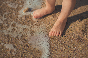 Child legs in a sand beach in summer time
