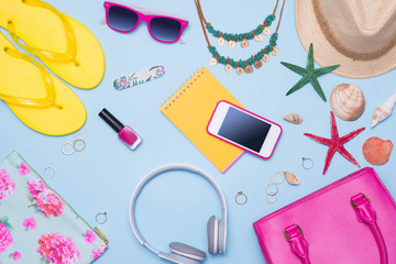 Summer concept. Pink handbag with accessories on light blue background