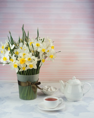Breakfast table setting with tea, teapot and spring flowers. Spring flowers background, vertical