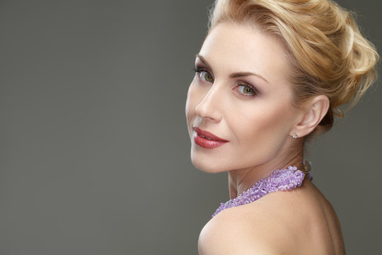 Incredible woman. Vertical shot of a stunning mature woman wearing necklace and professional makeup looking to the camera over the shoulder