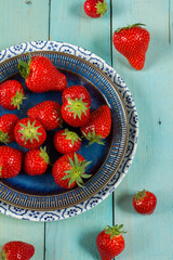 Fresh strawberries on blue plate. Isolated, wooden blue background.