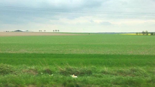 Landschaft mit Wiesen und W&auml;lder w&auml;hrend Zugfahrt in Deutschland aus Fenster der Bahn gefilmt