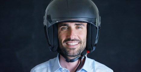 Portrait of a professional rider or motorcyclist, in a protective black helmet, on a black background. Concept: driver, drive, speed, protection, protective suit, reaction, love of extreme sports.	