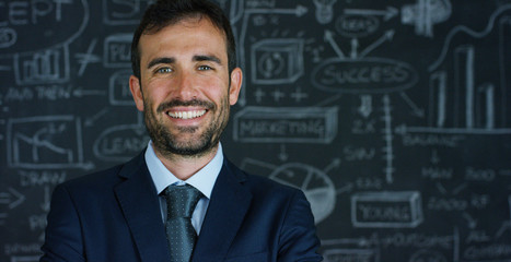 Portrait of a business man, a marketing teacher, draws a graph of success on a black board, on a black background. The concept: career growth, growth chart, successful man, marketing, ideas, finance.	