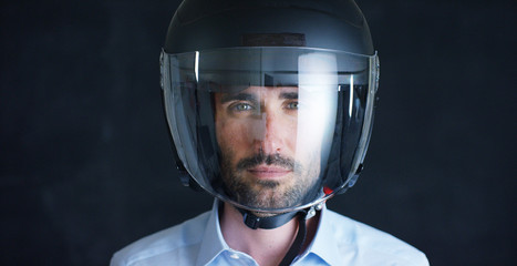 Portrait of a professional rider or motorcyclist, in a protective black helmet, on a black background. Concept: driver, drive, speed, protection, protective suit, reaction, love of extreme sports.	