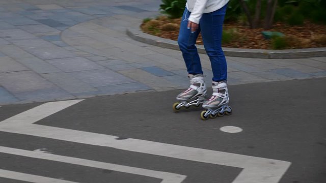 Feet of girl riding on a roller skates ride on asphalt. UltraHD stock footage.