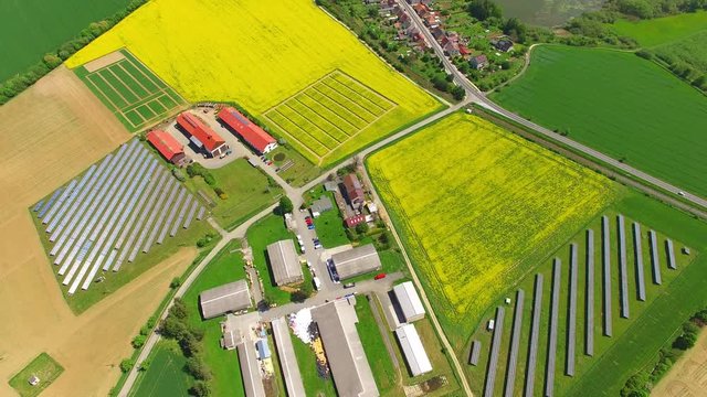 Aerial view to modern farm with organic produce. Agricultural landscape with green wheat and rapeseed fields from above. Sustainable development and renewable energy theme.