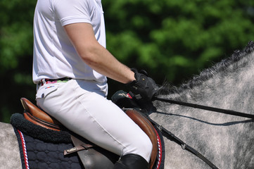 Fest im Sattel, Detailaufnahme von Reiter auf dem Pferd während eines Springreitturniers