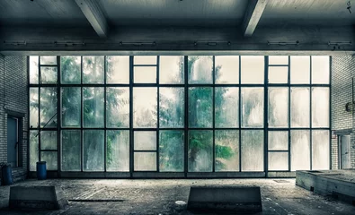 Tuinposter Het uitzicht vanuit een oude, verlaten fabriek aan de binnenkant met mooi raamlicht © Jani Riekkinen