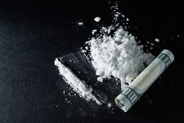 Cocaine and a folded hundred-dollar bill on a black background