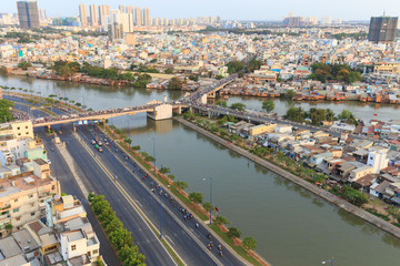 Obraz premium Ho Chi Minh city scape in Vo Van Kiet boulevard, canal, buildings and traffic around Cau Chu Y bridge, district 8