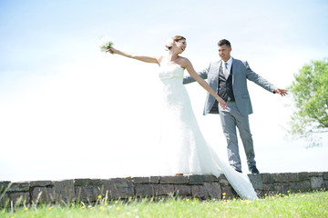 Bride and groom having fun walking on stone wall