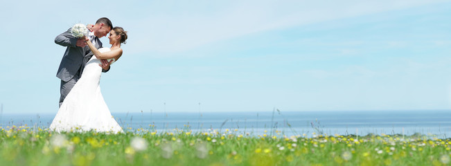 Bride and groom standing together in front of the sea