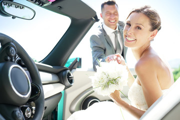 Groom leading bride to get in convertible car