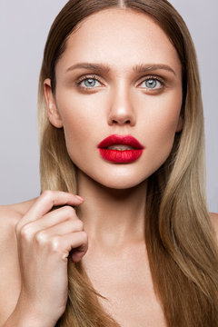 Beautiful young model with red lips and nude manicure
