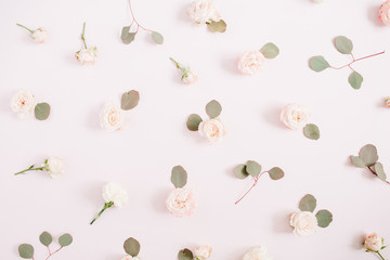 Flowers pattern texture made of beige roses, eucalyptus branches on pale pastel pink background. Flat lay, top view. Valentine's background. Floral texture background.
