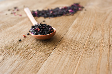 Fototapeta na wymiar Dry herbal tea with rose petals. Wooden background and spoon.