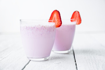 Blueberry smoothie with strawberry on white wooden table. Fresh milkshake