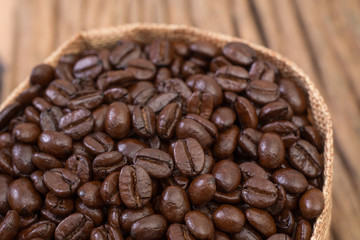Sack of coffee beans on wood background
