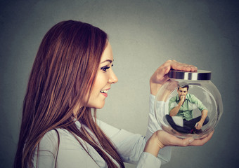 Woman holding a glass jar with imprisoned man in it