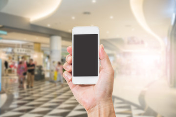 Hand holding mobile phone with blur shopping mall background