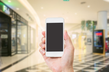 Hand holding mobile phone with blur shopping mall background