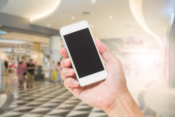Hand holding mobile phone with blur shopping mall background