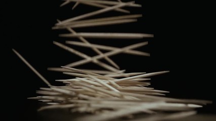 Slow motion. A lot of toothpicks fall down horizontally on a table black background - Powered by Adobe