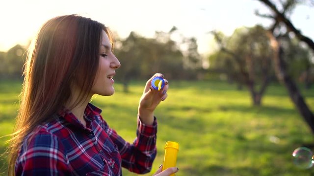 Woman blowing soap bubbles outdoors - slow motion
