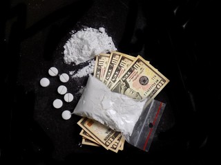 Cocaine drug powder bag, pile and line, pills and dollar money bills on black background