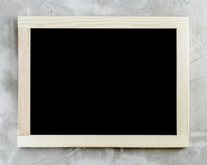 Blank black chalkboard with wooden frame on concrete background