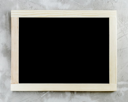 Blank black chalkboard with wooden frame on concrete background
