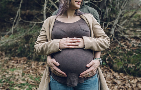 Man holding belly of pregnant woman in nature