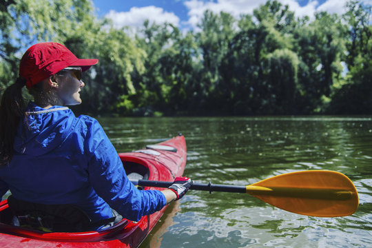 A girl rafts down the river on a kayak.