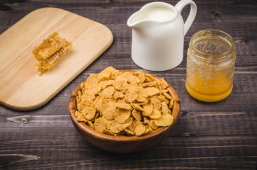 corn flakes, milk and honey on a wooden background/corn flakes, milk and honey