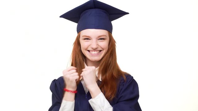 Young happy graduate Caucasian girl with gignger hair rejoicing on white background