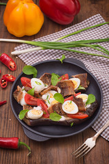 Baked eggplant with bacon, garlic and quail eggs on pan. Wooden background. Top view. Close-up