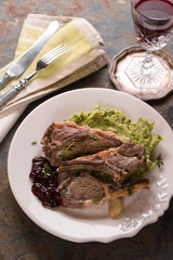 Serving of lamb ribs grilled, mashed potatoes, beetroot sauce, lemon, wine, napkin on the table